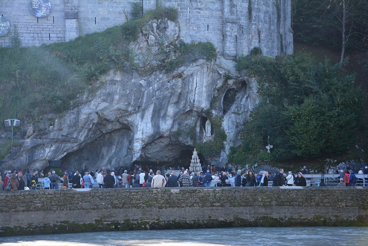 Des pèlerins devant la grotte de Massabielle au sanctuaire de Lourdes