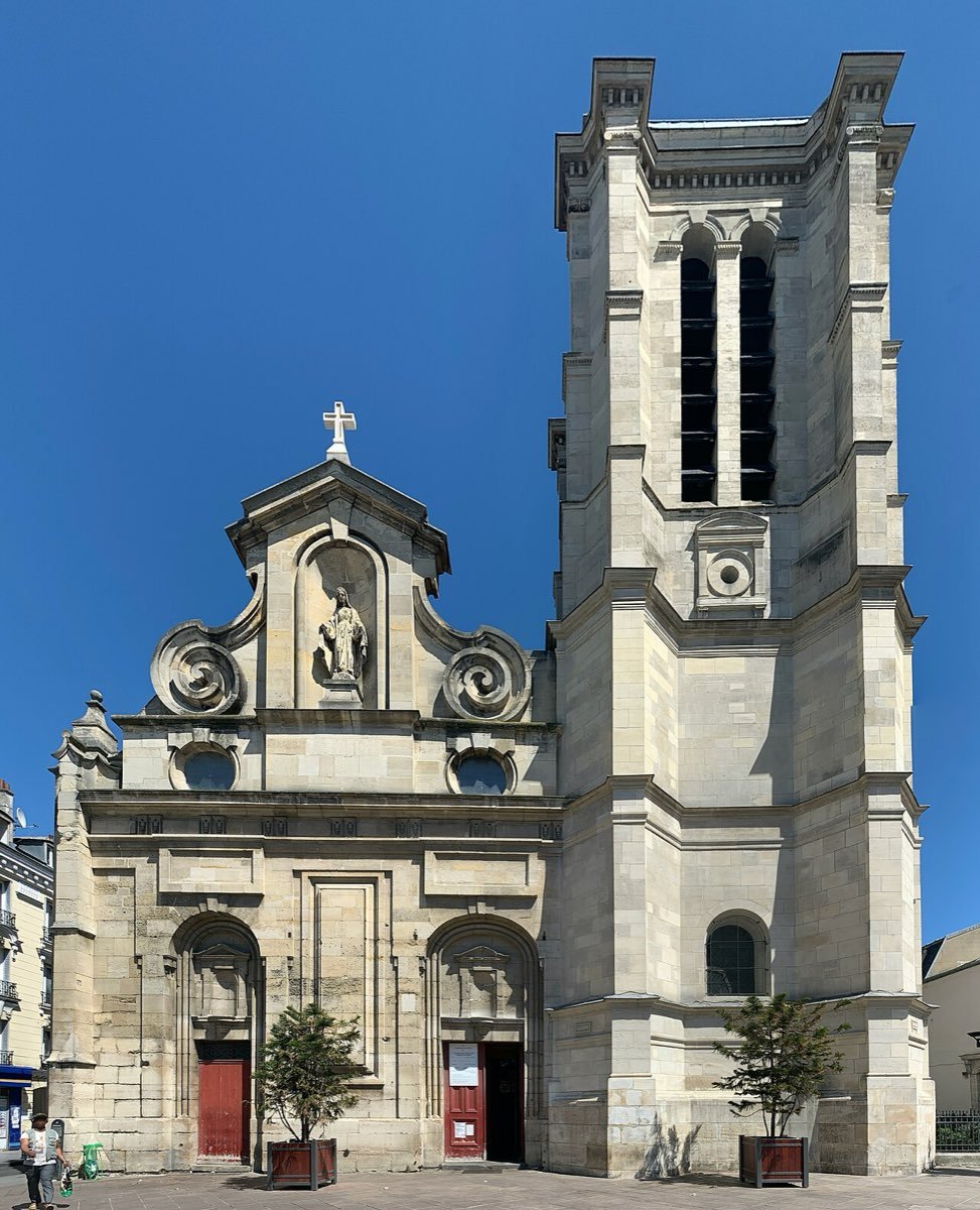 Façade classique et clocher carré de l'église Notre-Dame des Vertus à Aubervilliers, sous un ciel bleu
